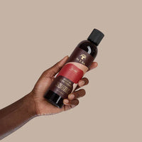 Hand hält As I Am Leave-In Conditioner, Haarpflege für lockiges und afro-texturiertes Haar