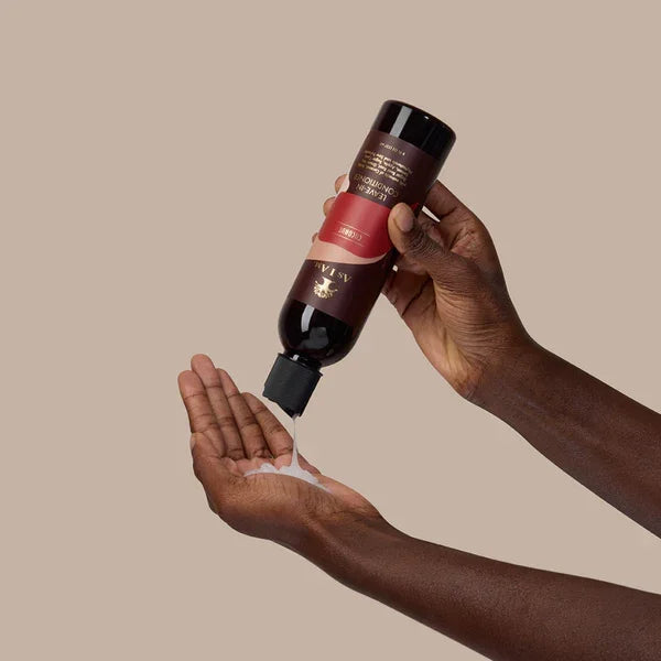 Hand hält Flasche Kokosnuss Leave-In Conditioner, gibt Haarpflege auf Handfläche