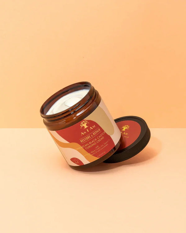 Jamaican Black Castor Oil Curling Creme für Locken in braunem Tiegel vor orange Hintergrund